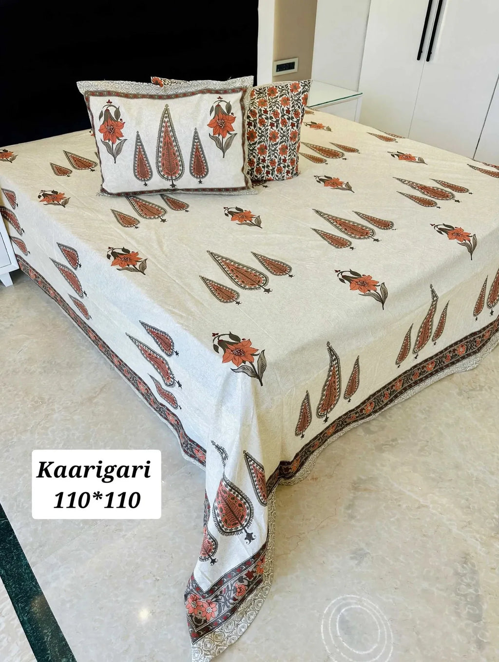 Orange floral print cotton bedsheet with two pillow covers on king size bed