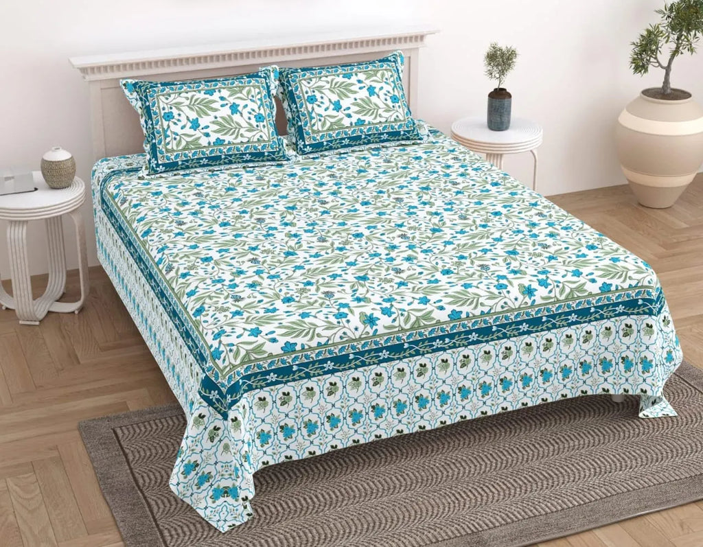 Teal blue botanical print pure cotton bedsheet on a bed with two matching pillows