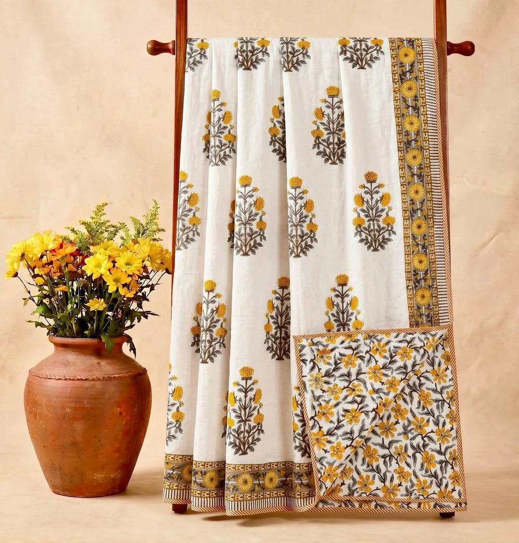 White cotton dohar featuring yellow floral hand block print displayed on wooden rack with clay pot