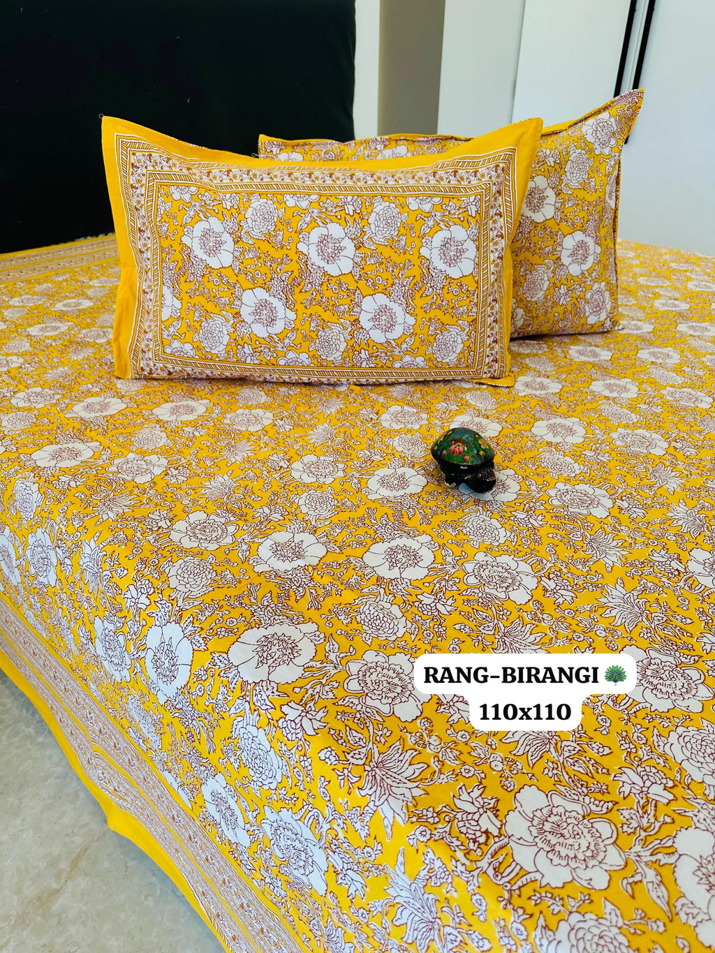 Yellow cotton bedsheet with white floral print and matching pillow covers on bed