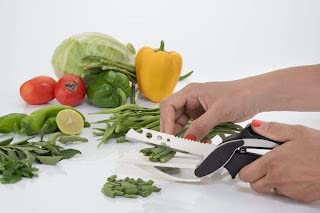 Close-up of the razor-sharp stainless steel blade slicing through a fresh red tomato.