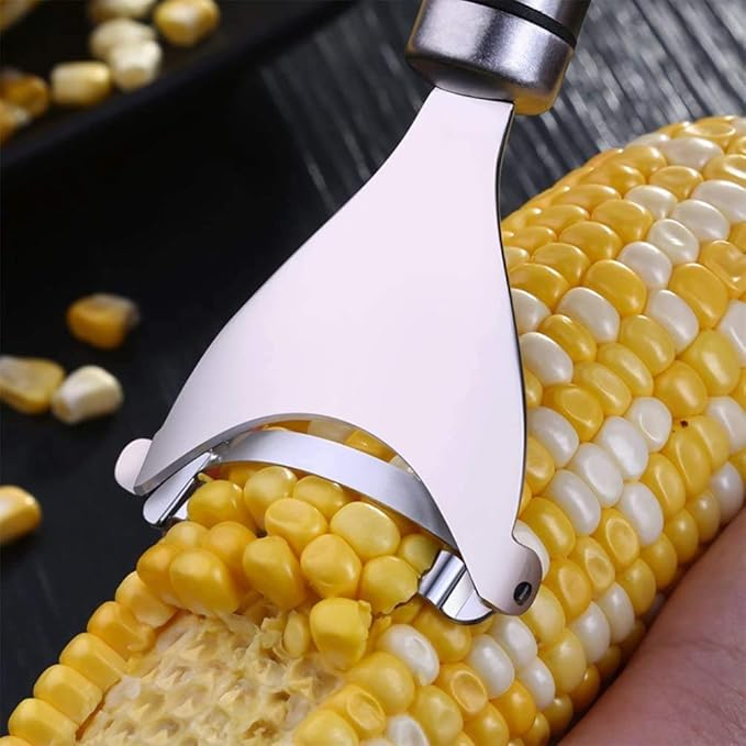 Silver stainless steel corn peeler with ultra sharp blades effortlessly removing kernels from a corn cob.
