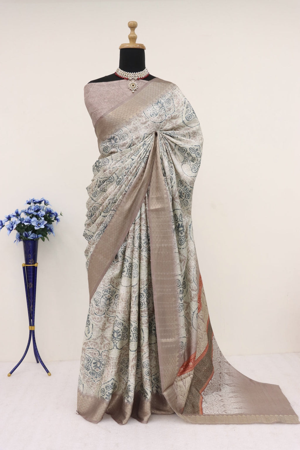 Light grey saree draped elegantly on a woman, showcasing its delicate fabric and subtle border design.