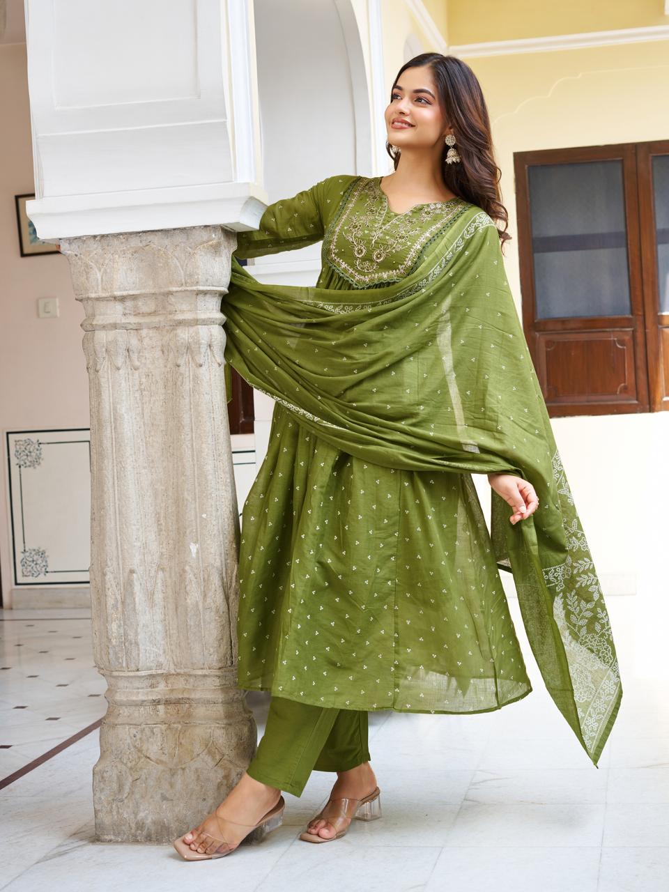 Model posing sideways in an olive green kurti set, with the printed dupatta draped around a pillar, highlighting the intricate pattern.