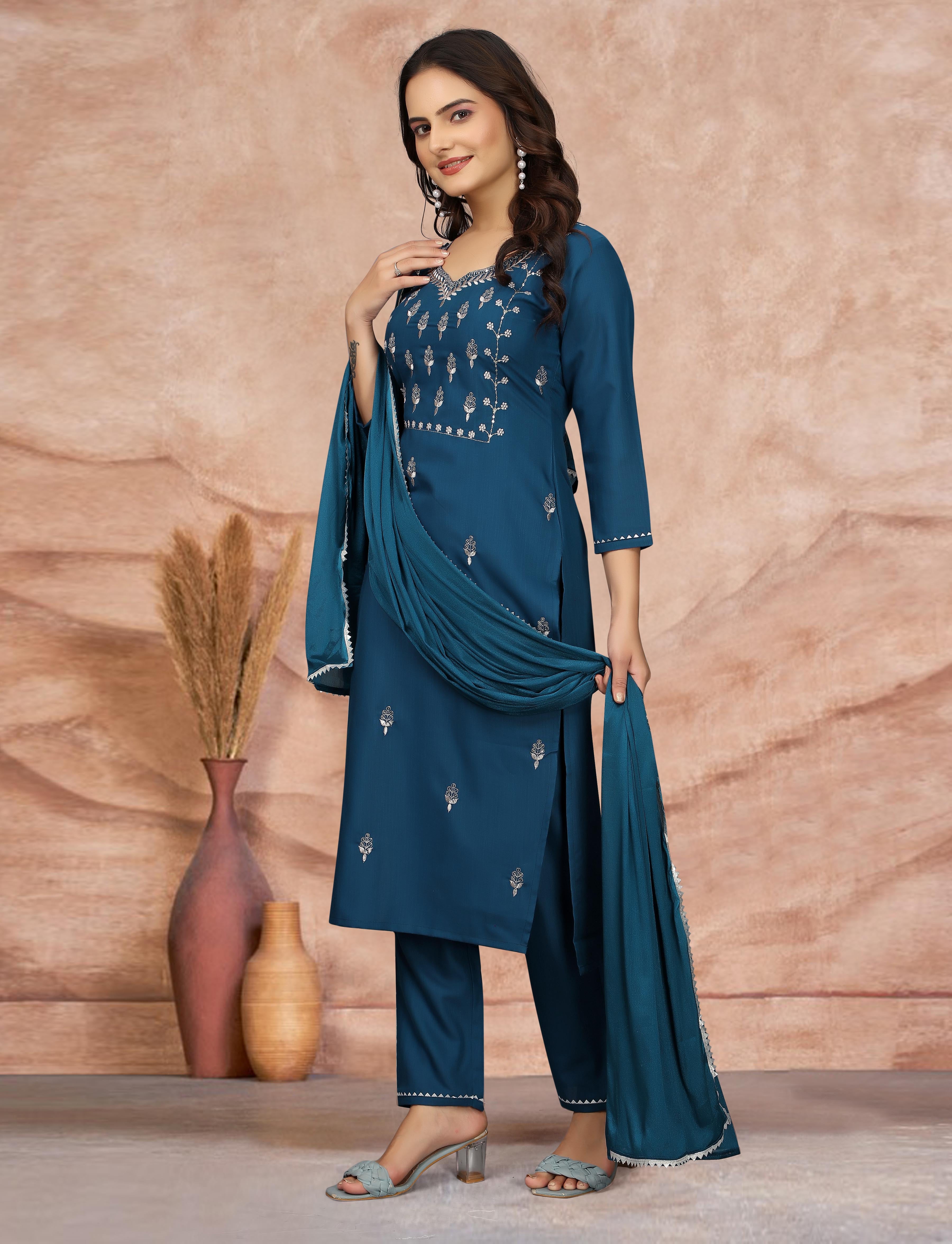 Woman in teal blue embroidered kurti set, posing with dupatta draped over arm, side view.
