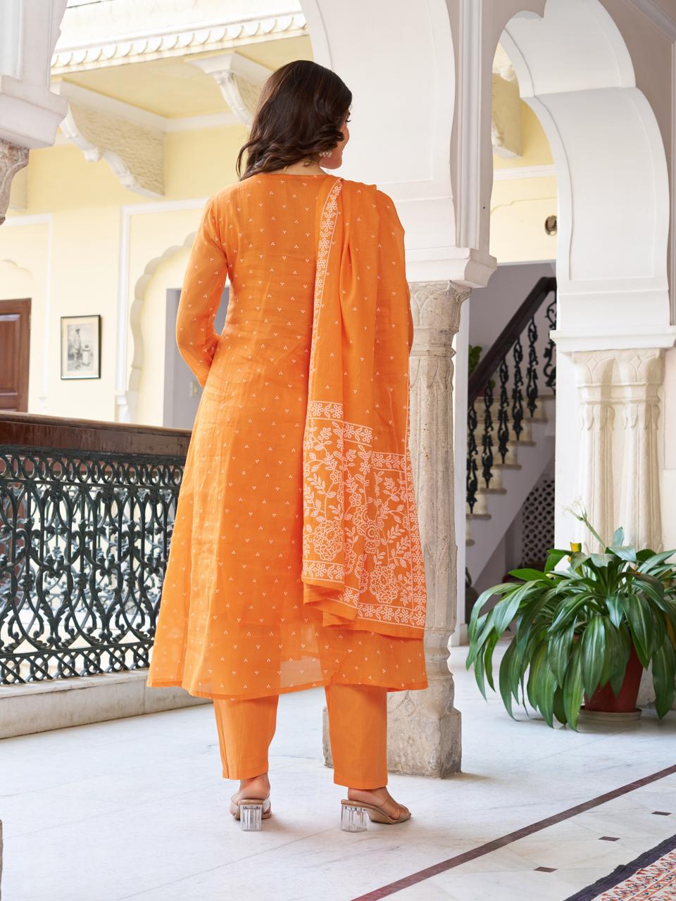 Back view of a model showcasing the full orange embroidered cotton kurti set, highlighting the simple pant and flowy printed dupatta.