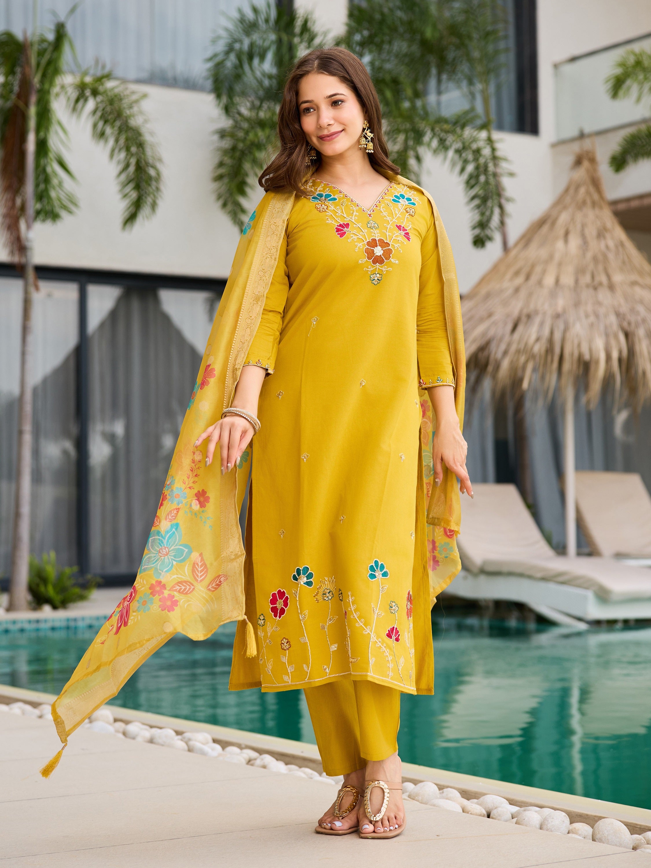 Full shot of model gracefully posing in yellow kurta set with dupatta flowing by the water.