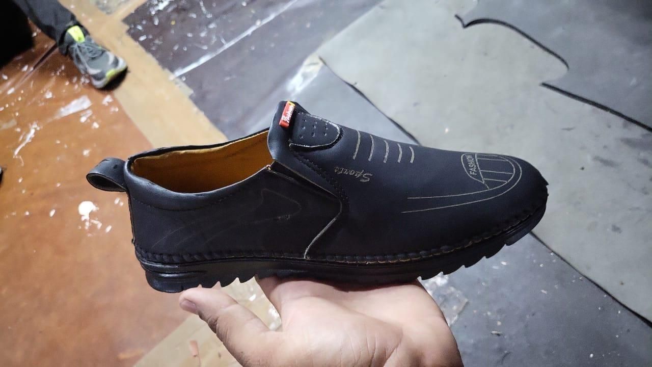 Black shoe held in a hand with a blurred background