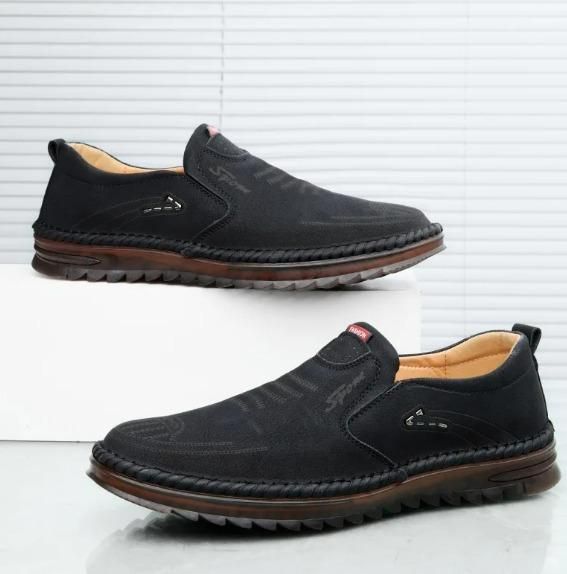 Black slip-on shoes with brown soles on a white background