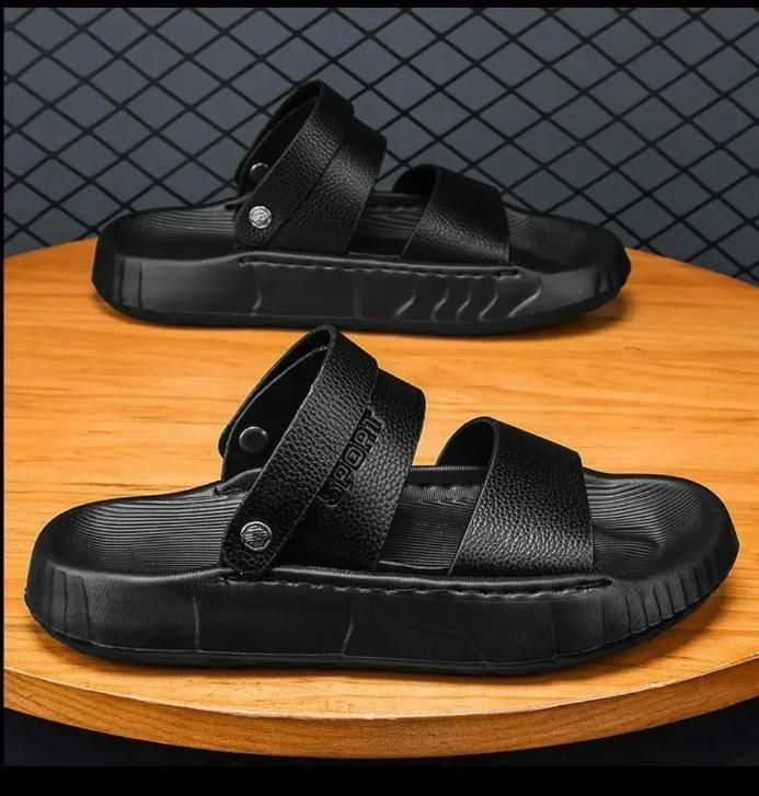 Black sandals on a wooden surface with a dark textured background