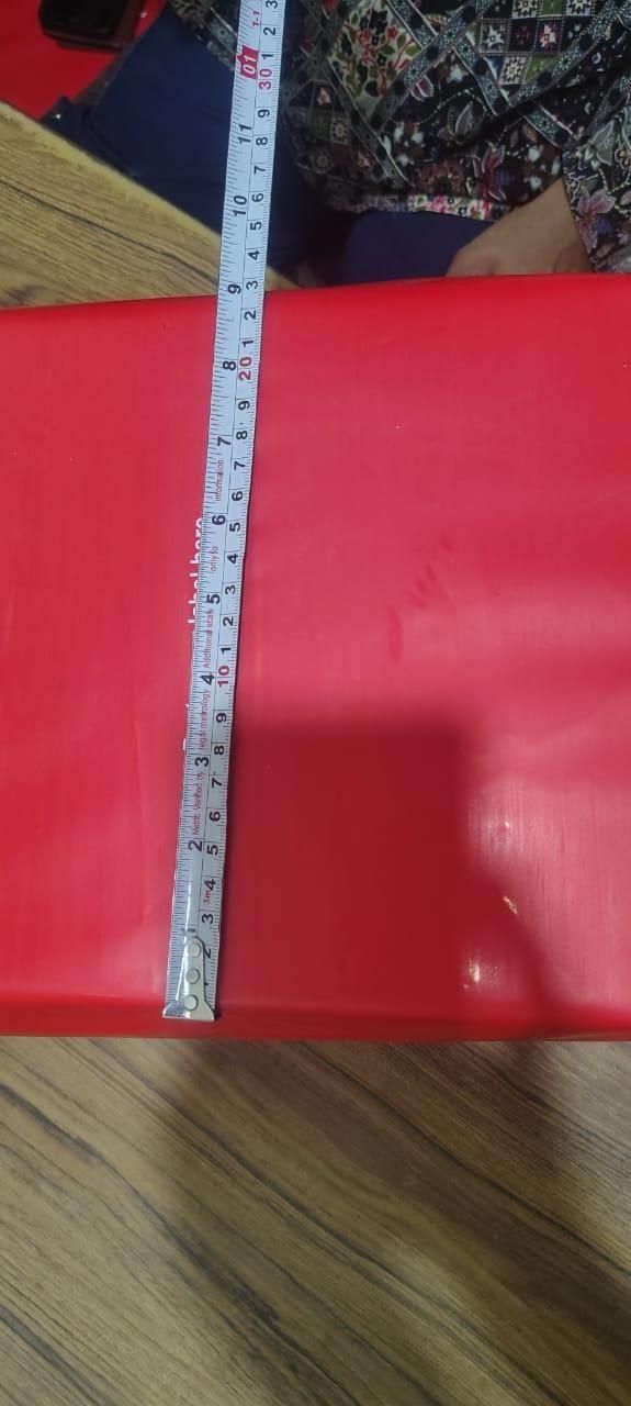 Metal ruler on a red box with a floral-patterned fabric background