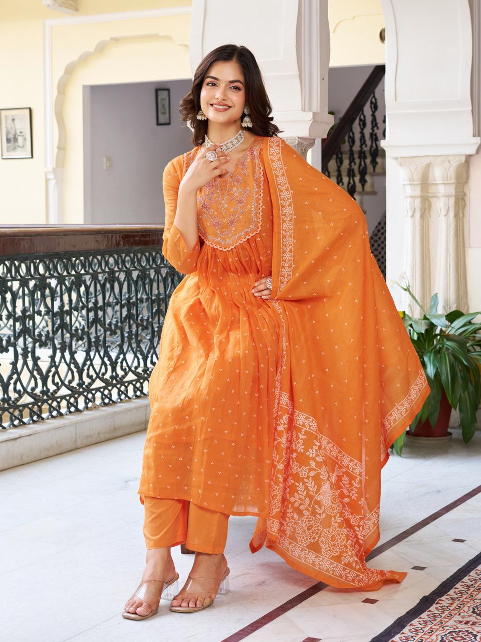 Model seated elegantly in an orange cotton kurti set, with dupatta draped over her shoulder, demonstrating the flared kurti style.