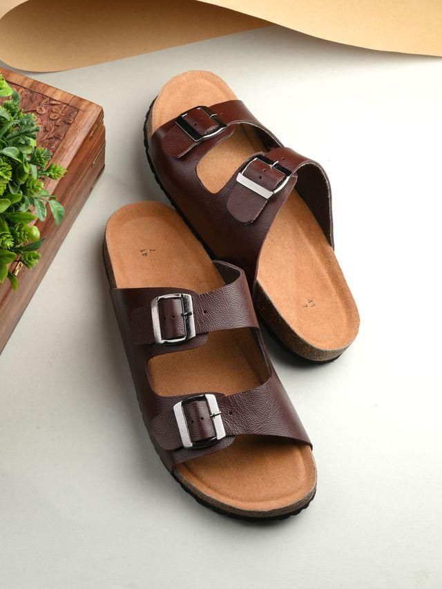 Pair of brown sandals with double buckles on a light gray surface.