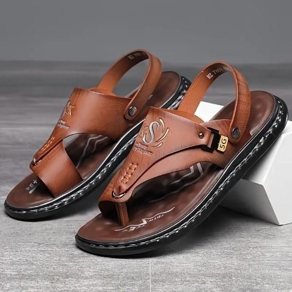 Brown leather sandals on a gray surface with a white block underneath.