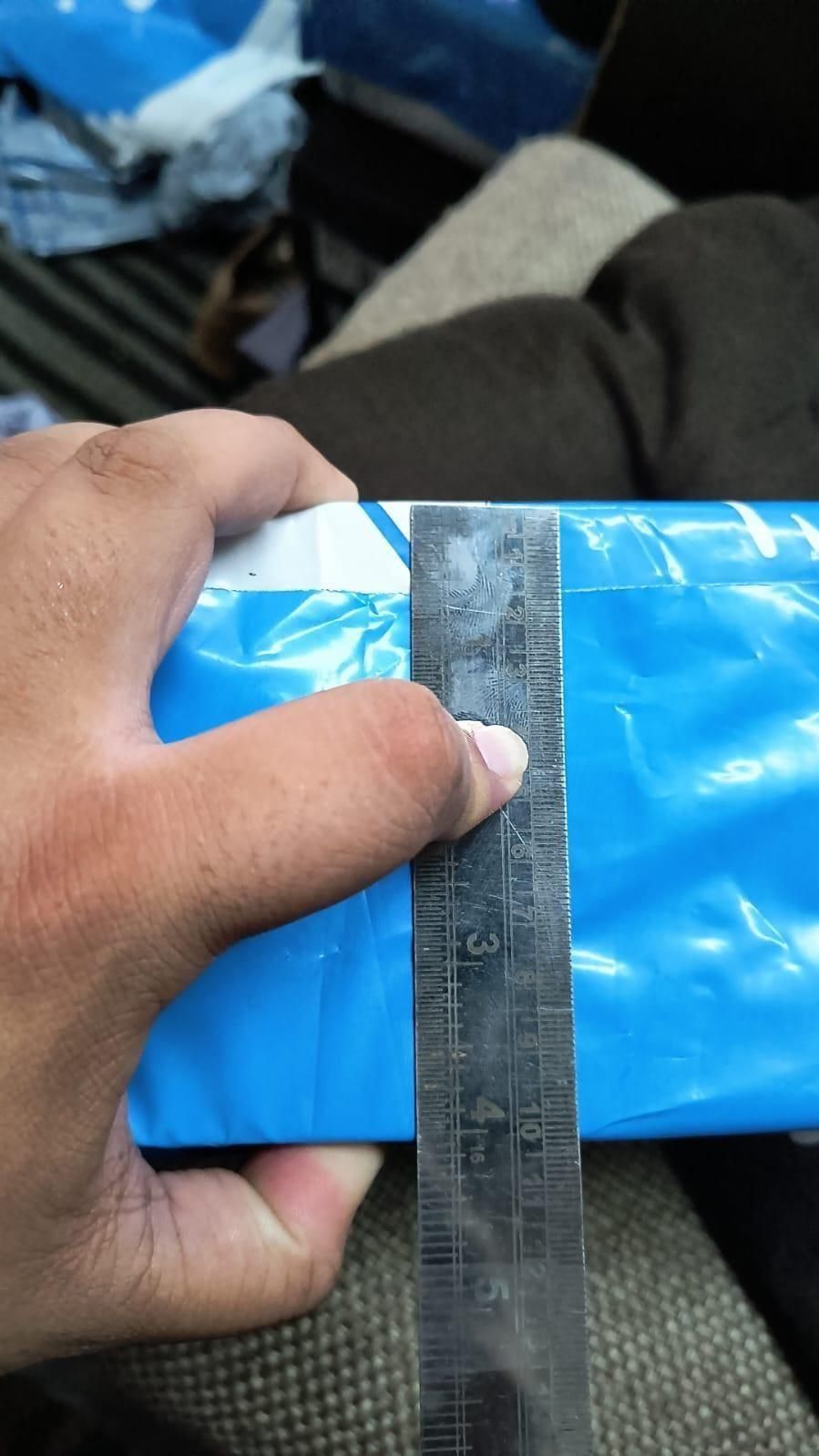 Hand holding a blue plastic sheet with a ruler for measurement