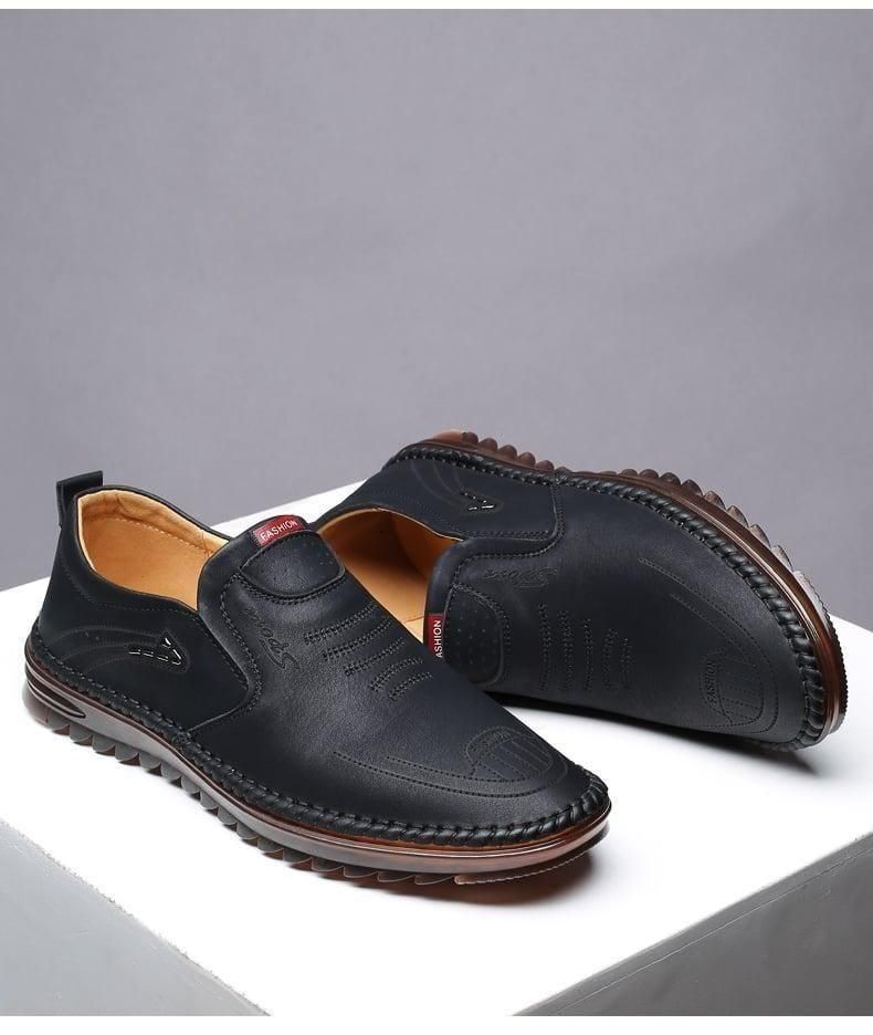 Black leather shoes with brown soles on a gray background