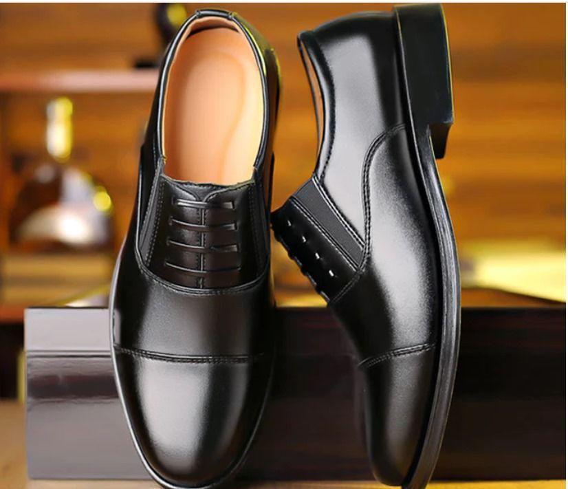 Pair of black dress shoes on a reflective surface with a blurred background