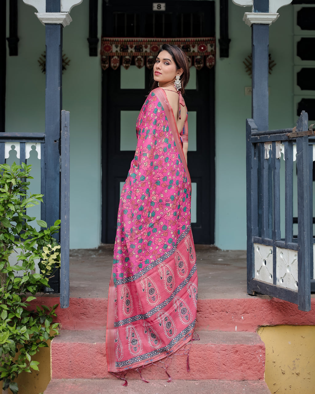 Close-up of pink linen fabric with green and peach floral prints and a classic paisley border