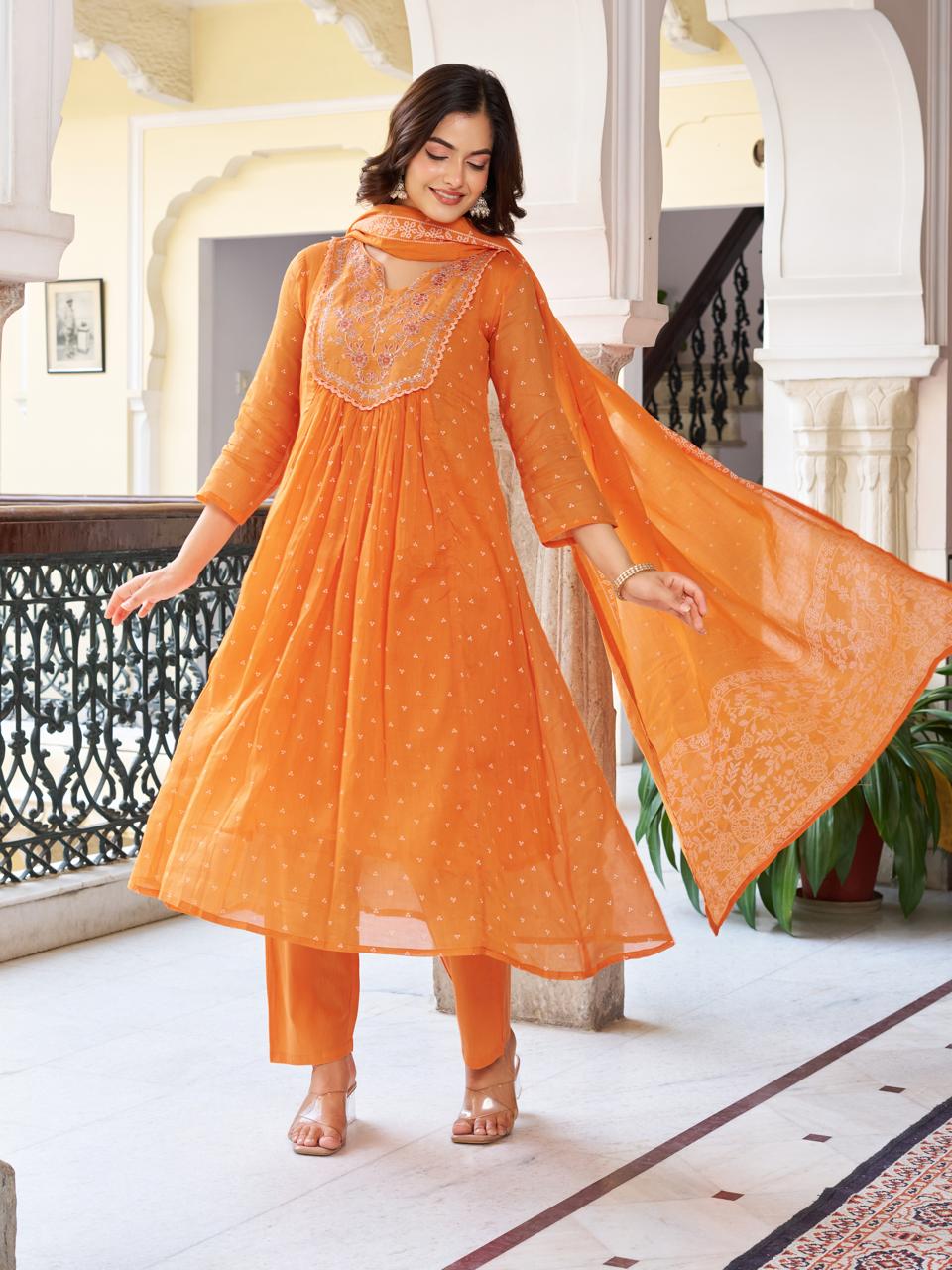Model striking a dynamic pose in a vibrant orange kurti set, with the printed dupatta flowing, emphasizing the graceful movement and design.