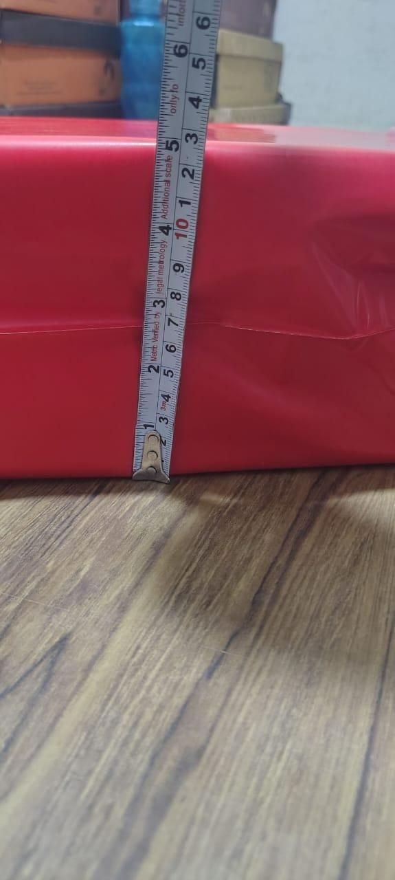 Red box with a ruler showing measurements on a wooden surface