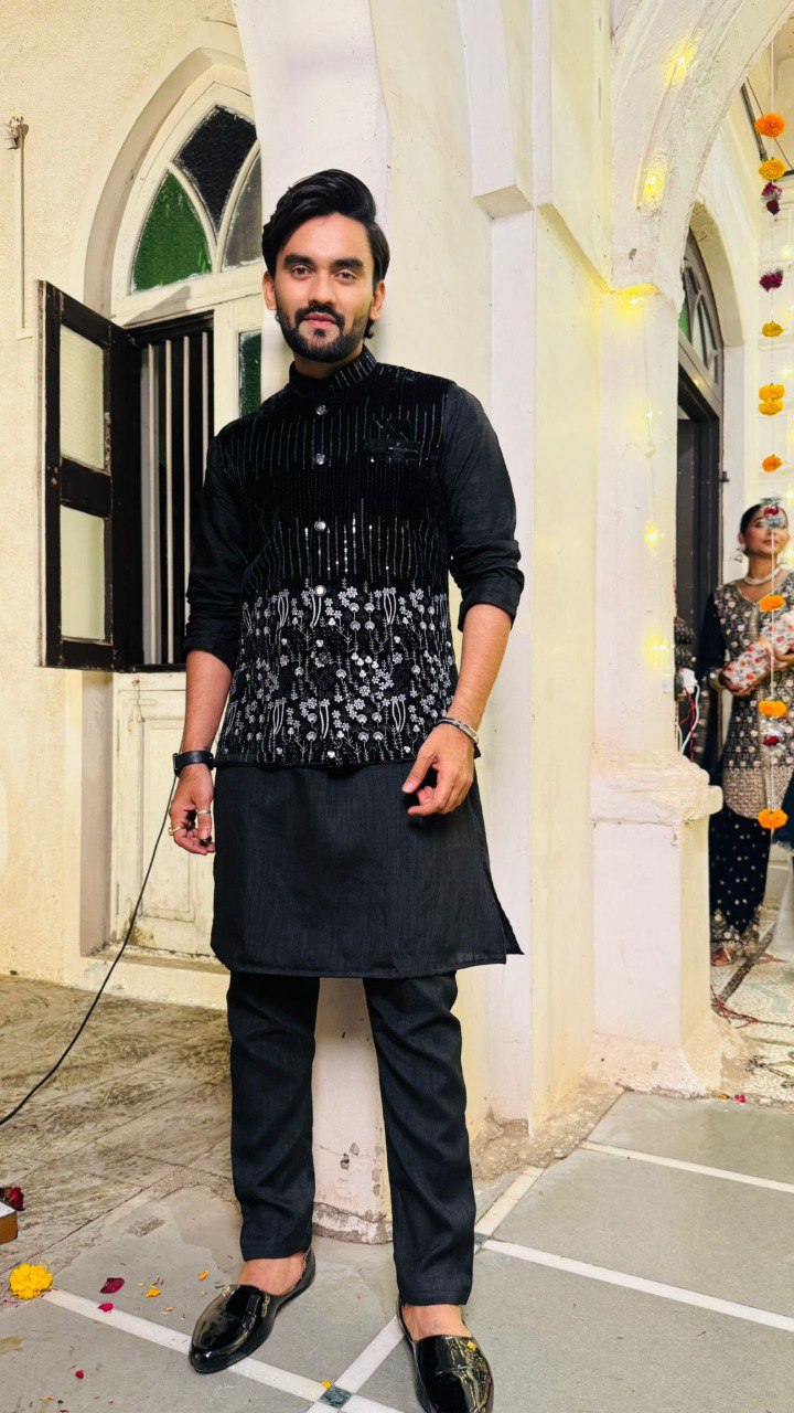 Man in traditional attire standing in a decorative indoor setting
