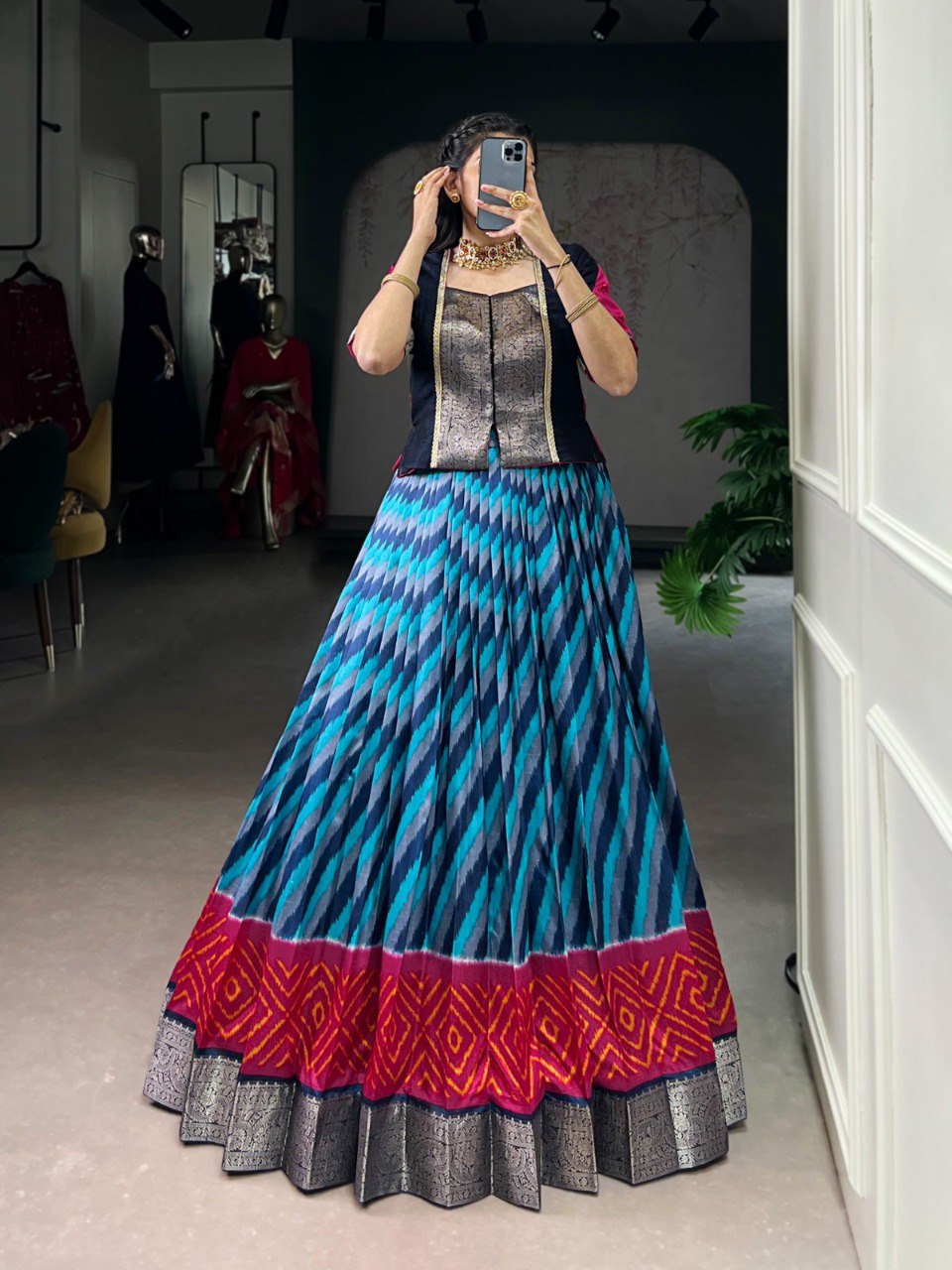 Model in blue leheriya print Tasar silk lehenga with a black zari weave Vichitra silk blouse and gold jewelry, front view.