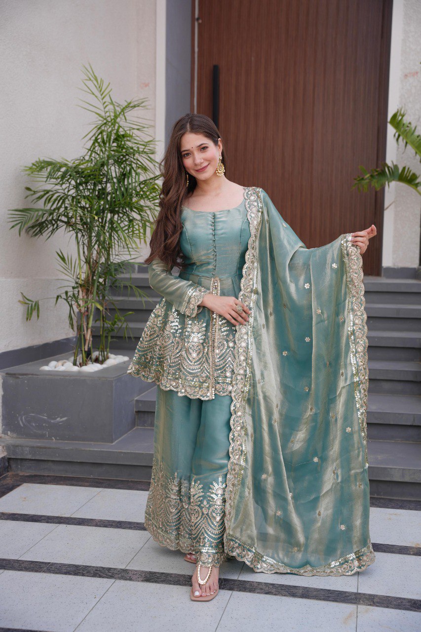 Full shot of a smiling model showcasing the teal peplum gown sharara suit with real mirror embroidery.