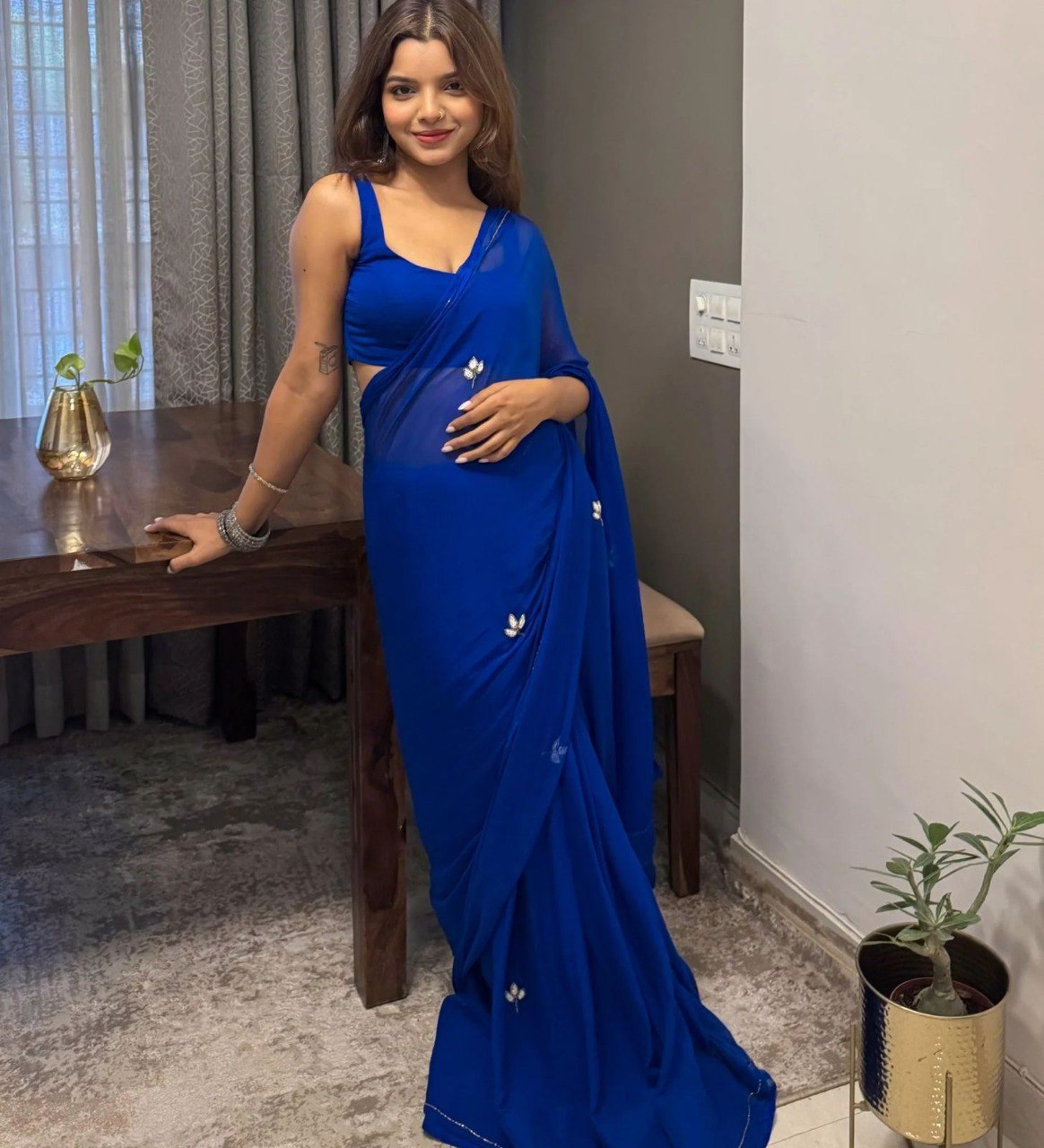Model gracefully posing in a royal blue handwork georgette dinner saree with leaf cut dana work.