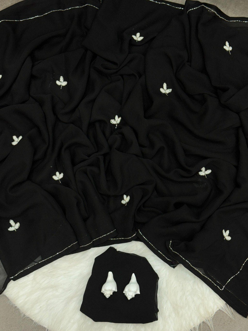 Detailed view of a black handwork georgette saree, showcasing the silver cut dana leaf patterns and elegant border, accompanied by the blouse piece.