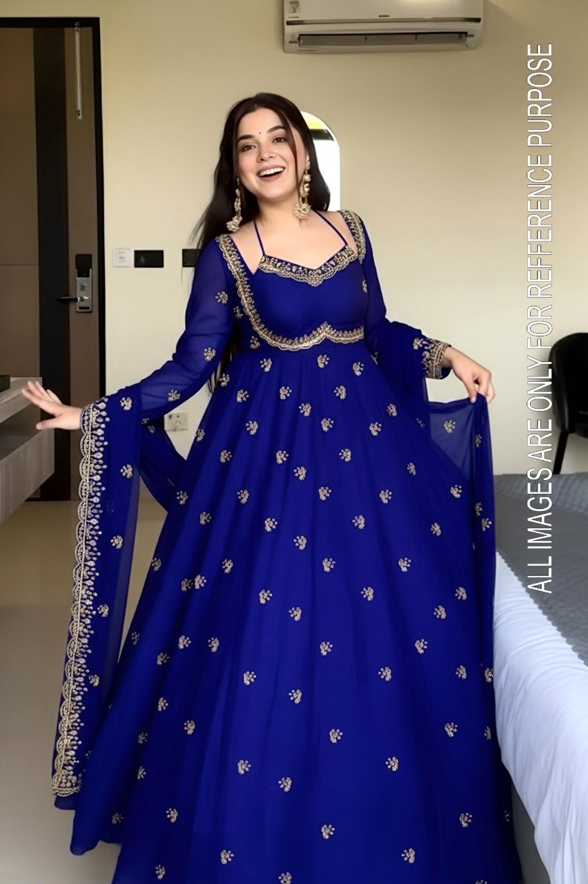 Smiling model showcasing a Royal Blue Faux Georgette Anarkali gown with golden zari embroidery, side view.