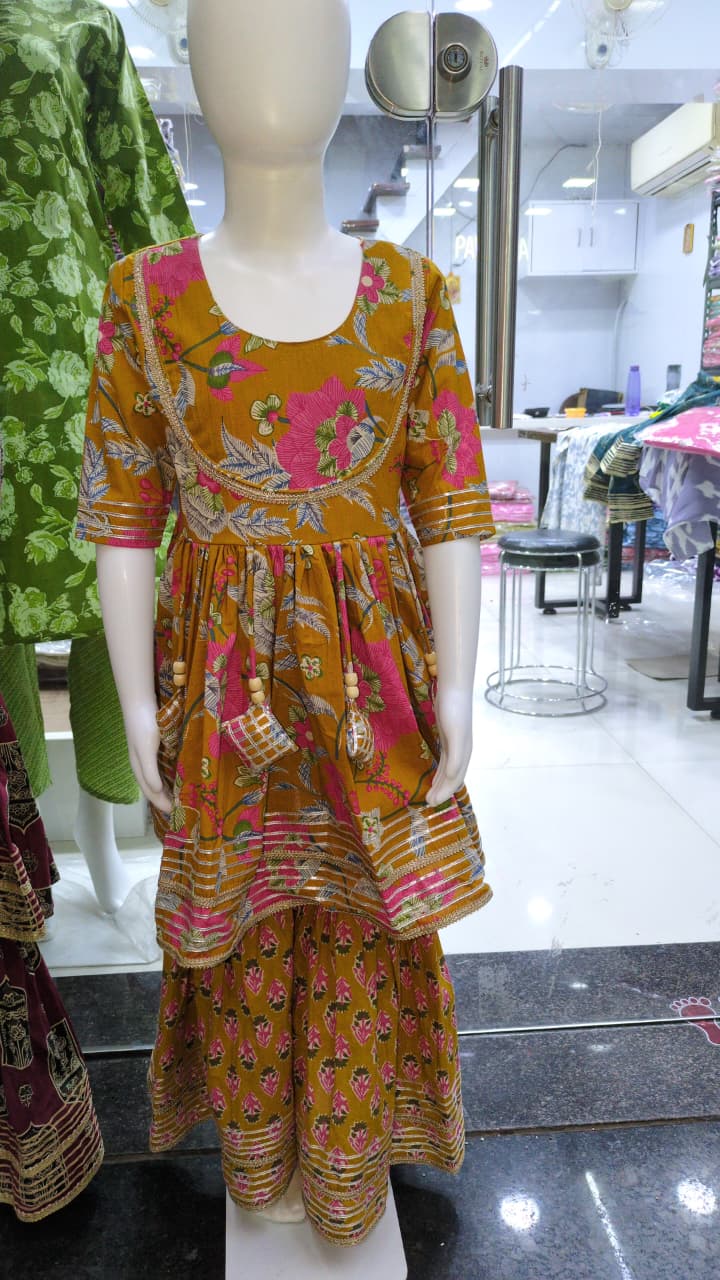 Mustard yellow floral print Kurta Kediya and Sharara set displayed on a child mannequin in a store setting, showcasing the design details.