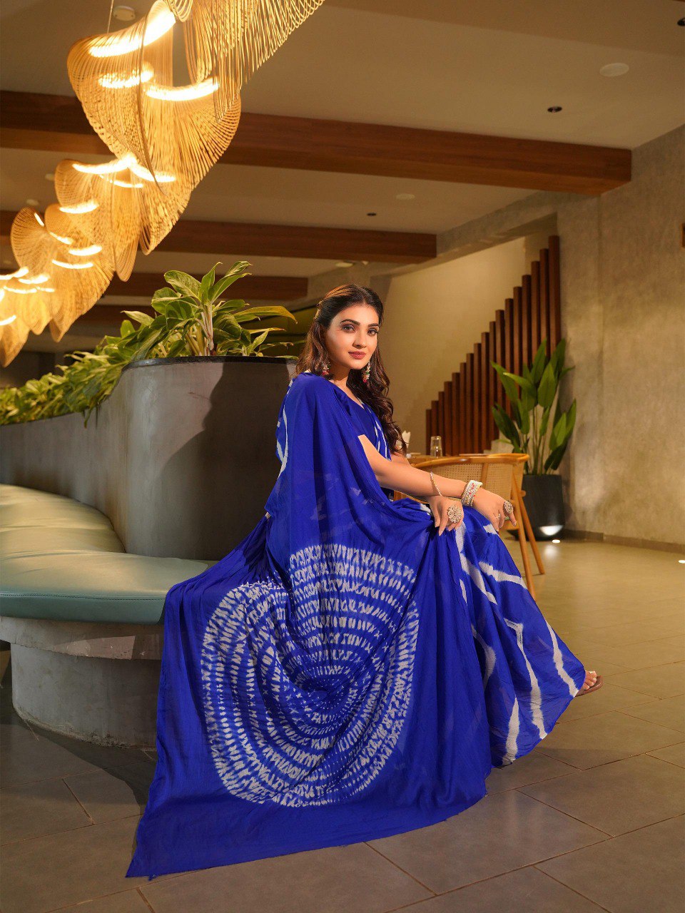 TRENDBUY model seated, showing off the intricate pallu of a royal blue Pure Chinoon Hand Shibori Laheriya saree.