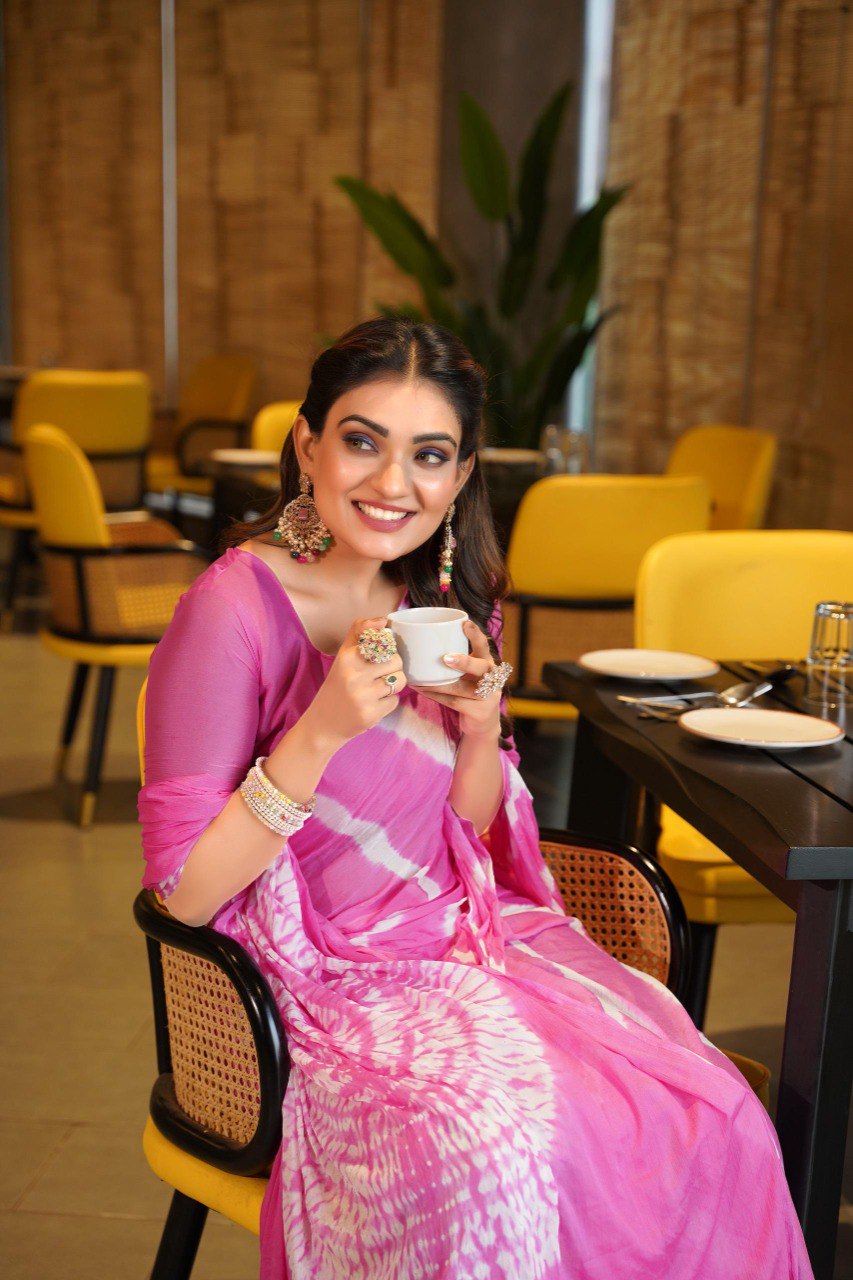 TRENDBUY model enjoying a beverage, wearing a bright pink Pure Chinoon Hand Shibori Laheriya saree.