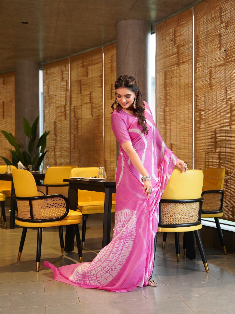 TRENDBUY model gracefully adjusting her bright pink Pure Chinoon Hand Shibori Laheriya saree.