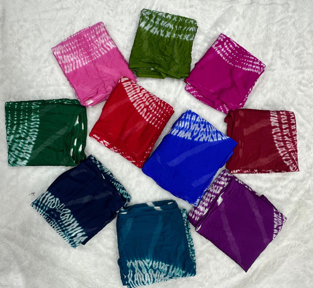 Flat lay display of 10 vibrant colors available for the Pure Chinoon Hand Shibori Laheriya Saree by TRENDBUY.