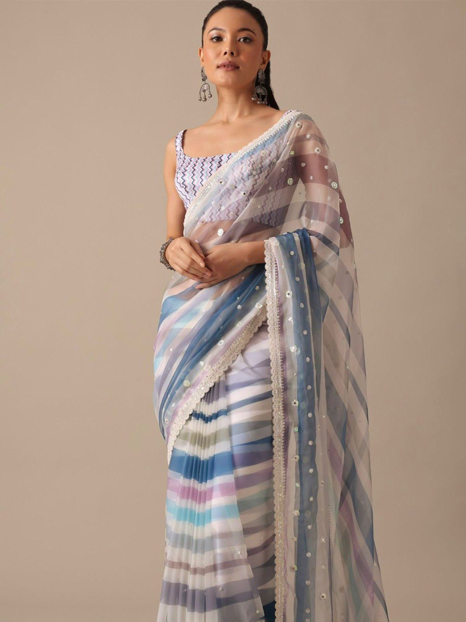 Model wearing a blue and purple striped georgette saree with sequin work and a blue chevron print blouse, showcasing front drape.