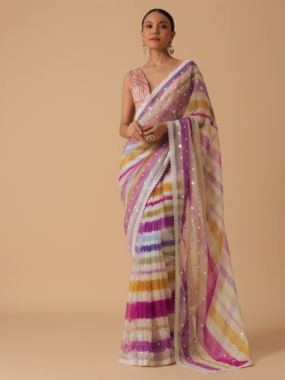 Model wearing a pink and yellow striped georgette saree with sequin work and a colorful chevron print blouse, showcasing front drape.