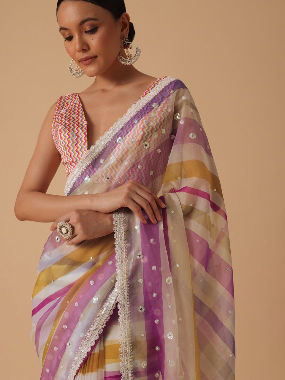 Close-up of model in pink and yellow striped saree, highlighting sequin details, cutwork border, and chevron print blouse.