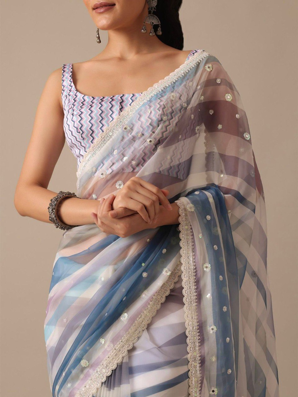 Close-up of model in blue and purple striped saree, detailing sequin embellishments, cutwork border, and chevron blouse.