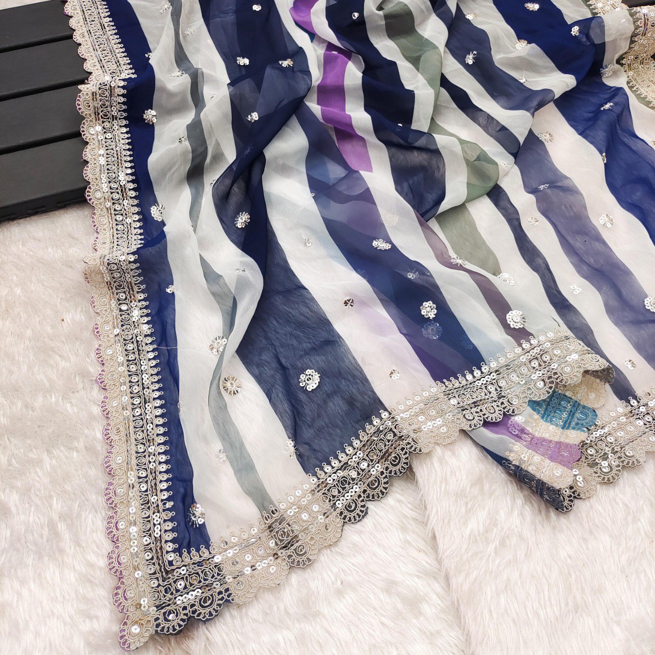 Detailed flat lay of the blue and purple striped georgette saree border with sequins and intricate cutwork.