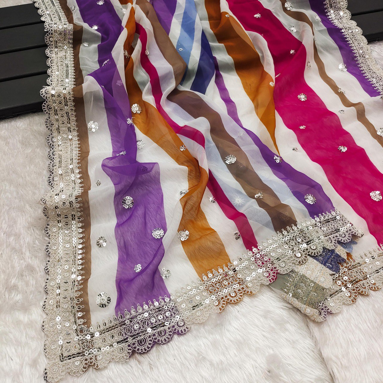 Close-up of the pink and yellow striped georgette saree with sequins and the elegant cutwork border detail.