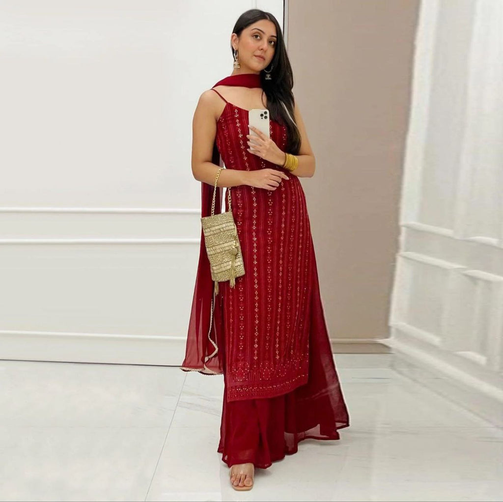 TRENDBUY model in a red georgette sleeveless suit set with intricate gold embroidery and sequence work, holding a matching gold clutch.