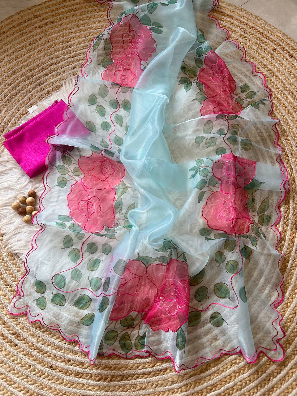 Close-up of intricate hand-stitched Aari embroidery and delicate cutwork border on pink organza fabric
