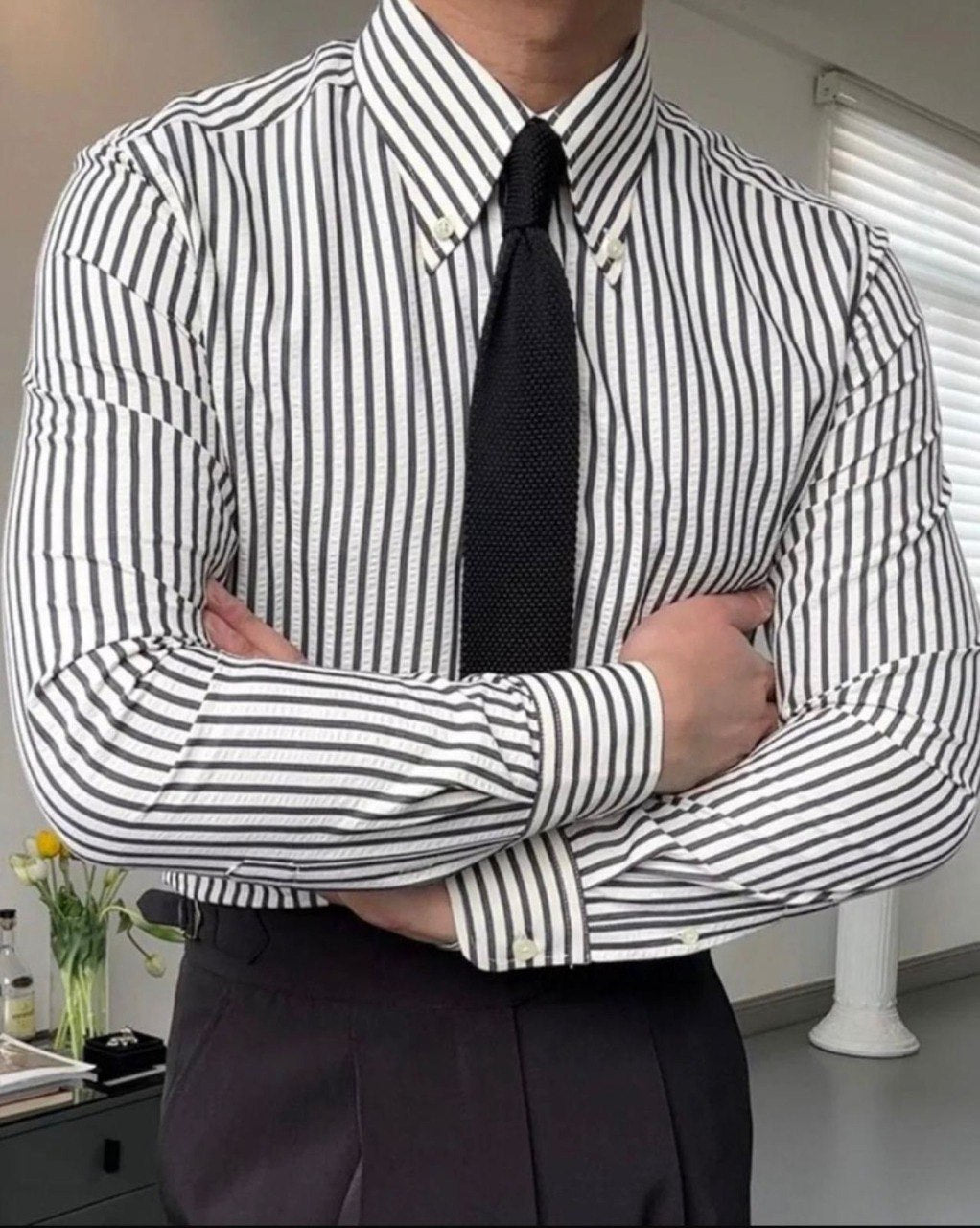 Trendy men's black and white striped button-down shirt with black tie, arms crossed, perfect for formal occasions