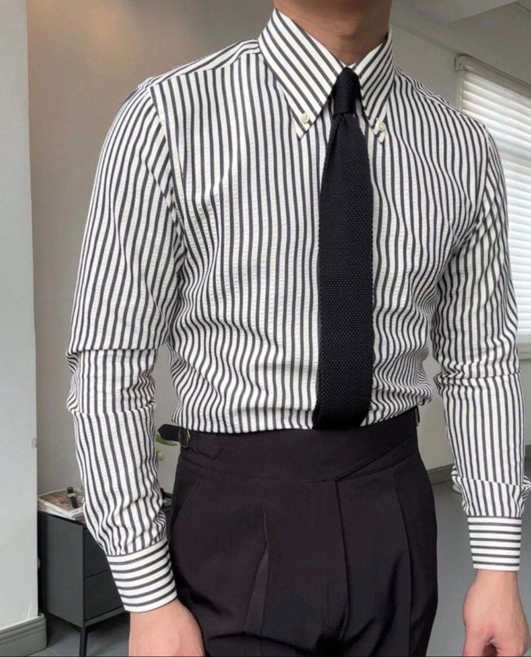 Stylish black and white vertical striped shirt for men, paired with a black tie and dark pants, exuding sophistication
