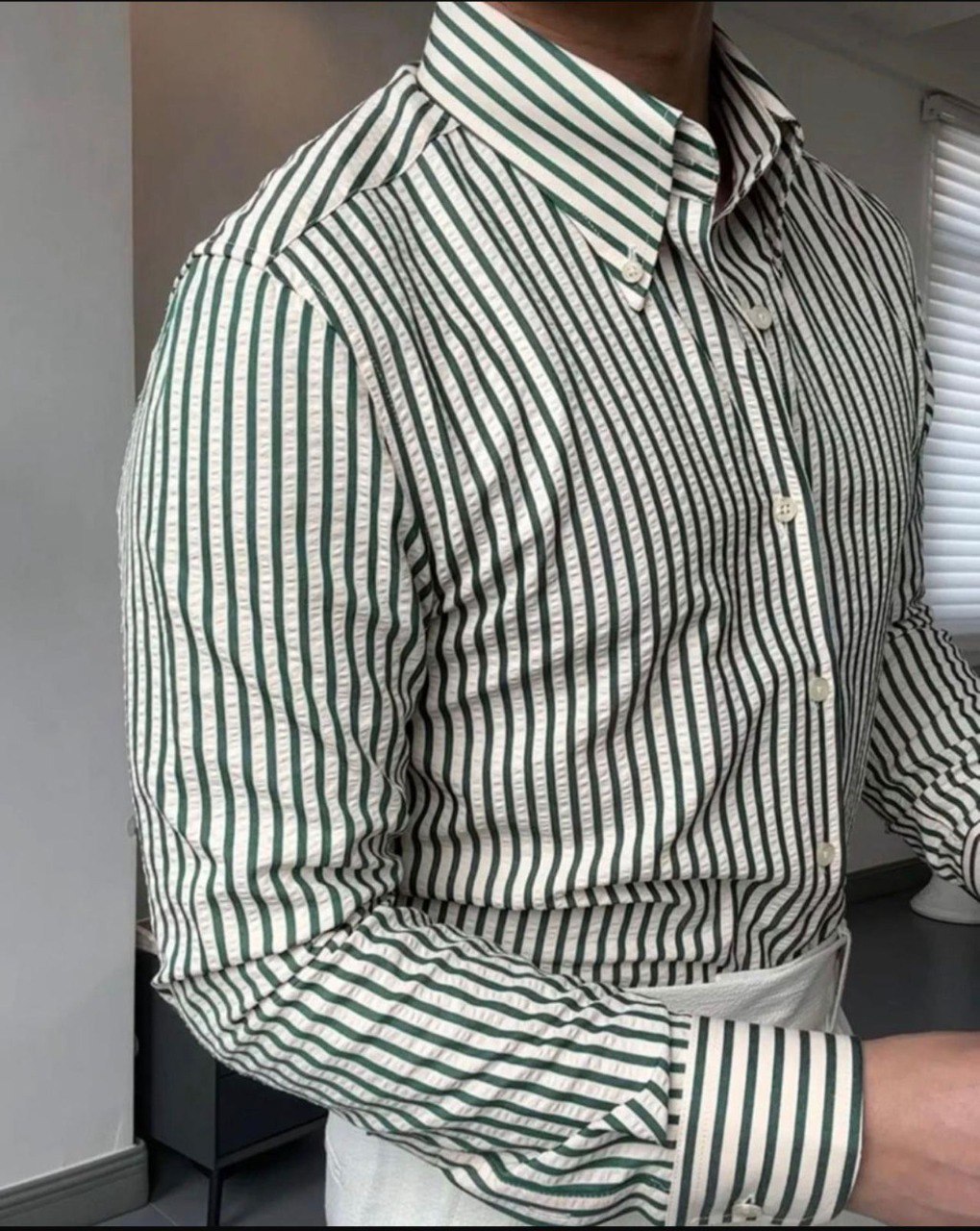 Close-up of green and white fine vertical striped men's shirt fabric and buttons, highlighting quality