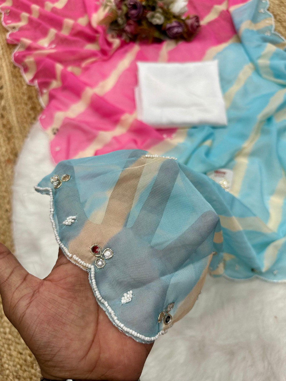 Hand holding blue Lehriya Tebi silk fabric swatch, highlighting transparent texture and mirror work details.