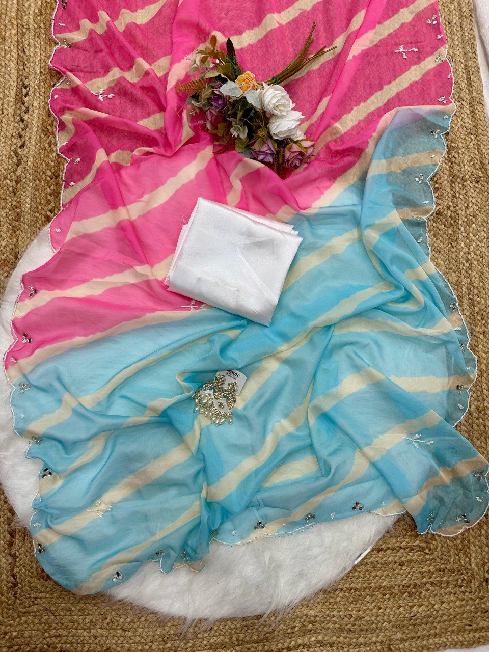 Full spread of a radiant pink and blue Lehriya Tebi silk saree with its matching white satin silk blouse piece.