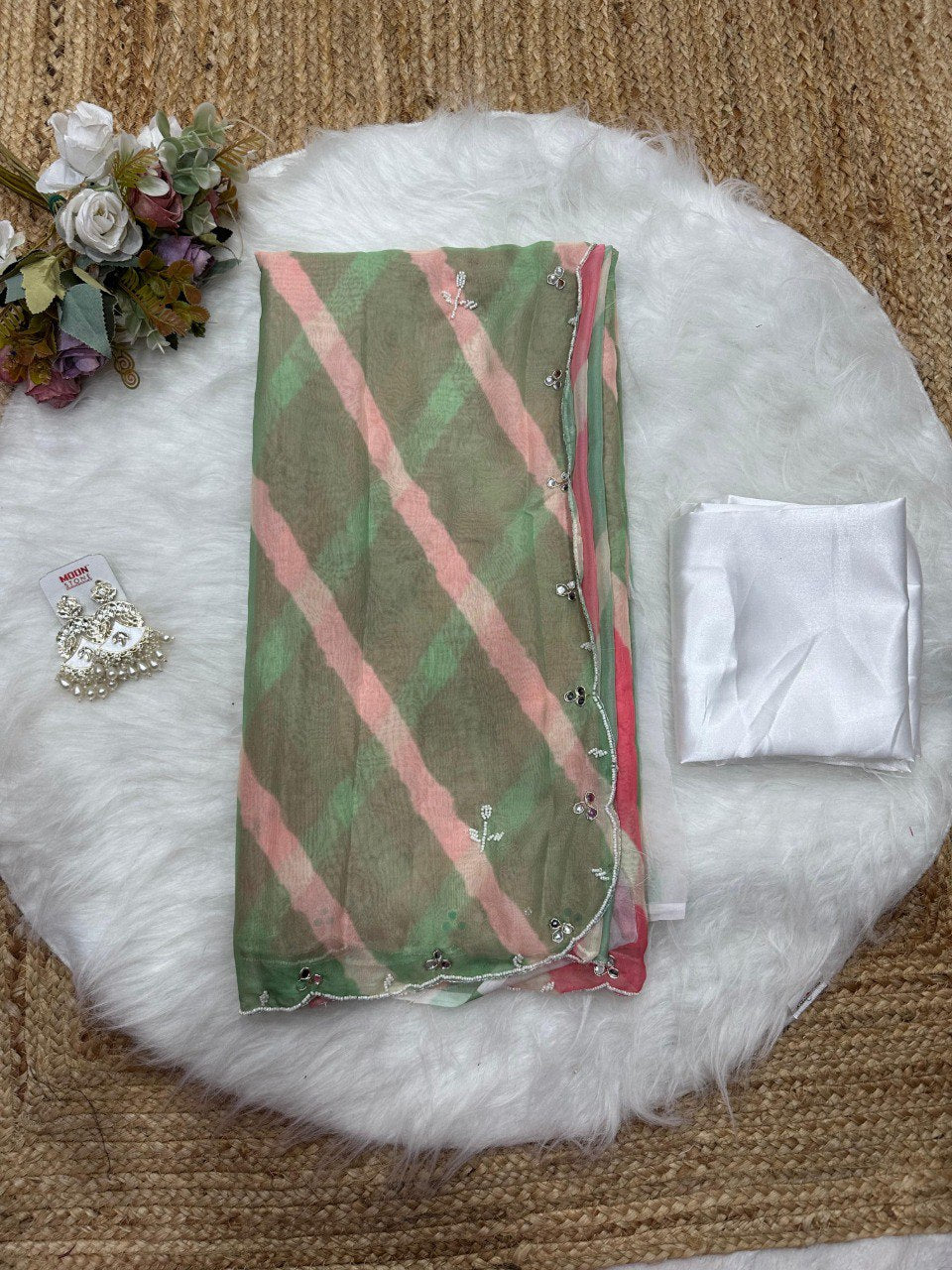 Neatly folded pink and green Lehriya Tebi silk saree displayed with its soft satin silk blouse piece.