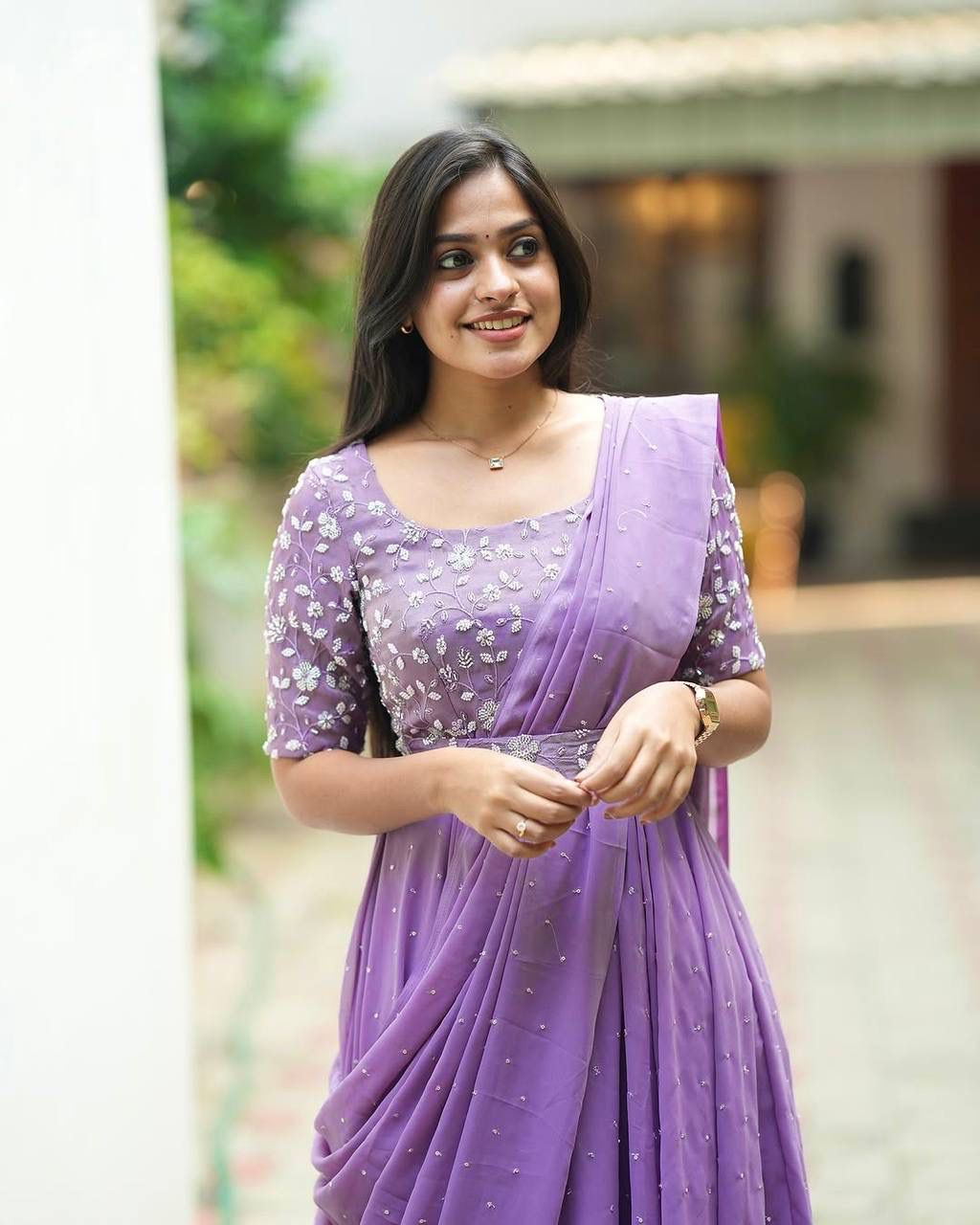 Close-up of model smiling in a lavender georgette gown, highlighting the intricate 5mm sequins and thread embroidery on the bodice and sleeve.